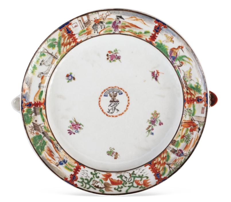 圖為清嘉慶廣彩描金花卉人物紋章溫盤，盤沿兩側(cè)對稱置半圓形注水口。外邊飾為鄉(xiāng)村風景紋，盤心繪紋章，四周繪六組折枝花卉圍繞。溫盤又稱暖盤，使用時將熱水由孔注入，使盛入淺盤的食物保溫，達到防冷溫熱的效果。（來源：廣州十三行博物館）